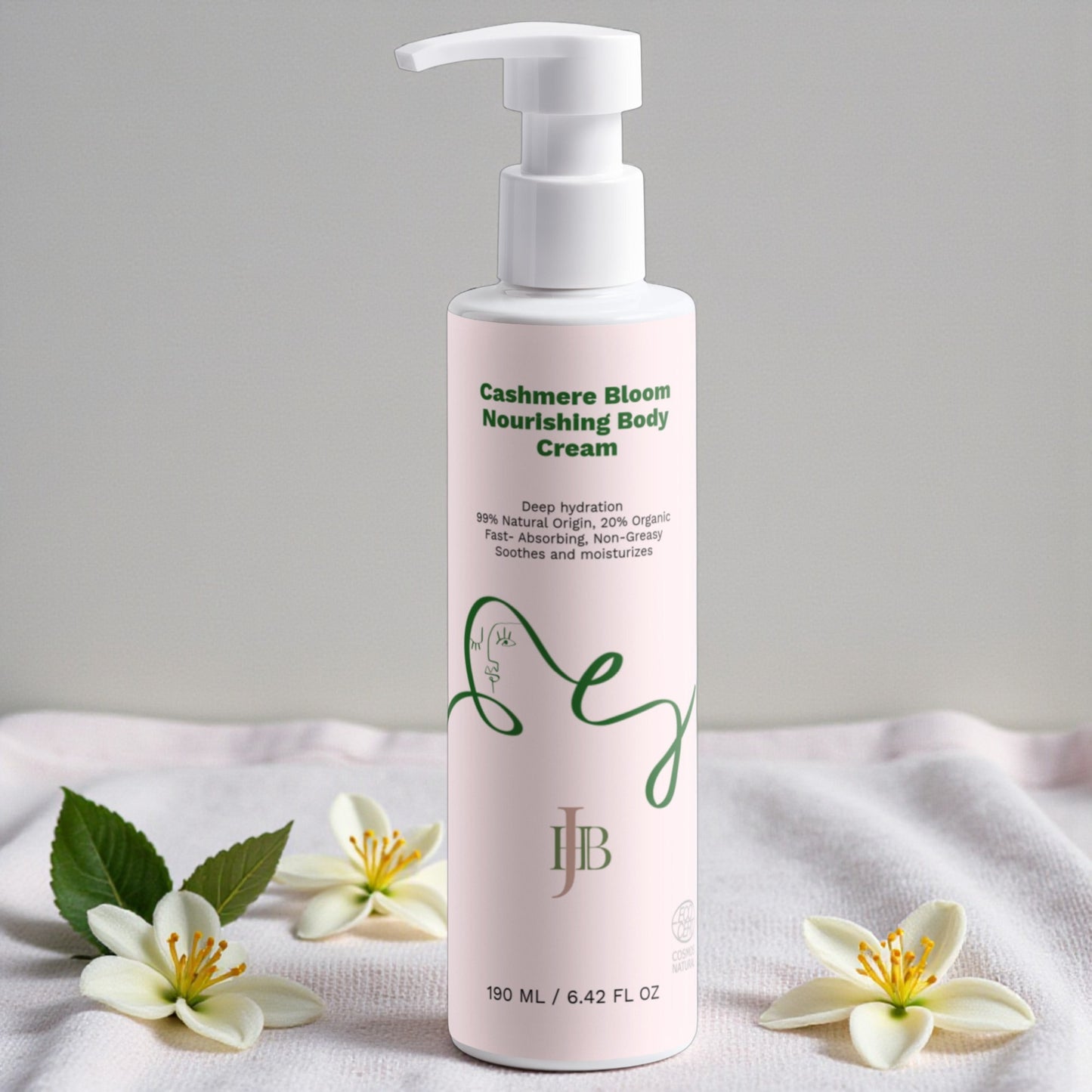 Bottle of Cashmere Bloom Nourishing Body Cream with flowers on a white fabric background